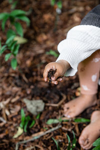 Lapsi pitelee metsän multaa kädessään
